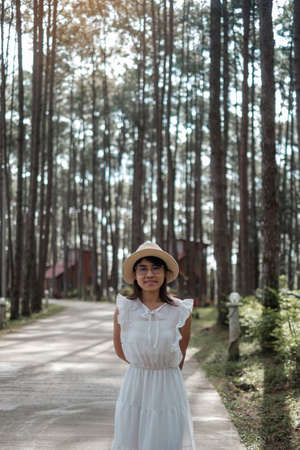 Happy woman in white dress and hat traveling in pine tree forest, tourist visit at Doi Bo Luang, Chiang Mai, Thailand, Landmark and popular for tourist attractions. Vacation and journey conceptの写真素材