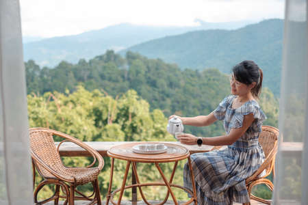 woman drinking tea and looking mountain view, young blogger stay at countryside homestay in the morning.Travel, vacation, journey, trip and relaxing conceptの写真素材