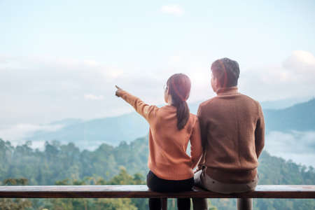 Couple tourist relaxing and looking mountain view at countryside home or homestay in the morning. Vacation, together travel, honeymoon, blogger, journey, trip and relaxing conceptの写真素材