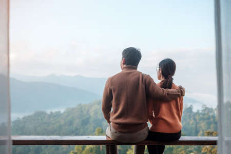 Couple tourist relaxing and looking mountain view at countryside home or homestay in the morning. Vacation, together travel, honeymoon, blogger, journey, trip and relaxing conceptの写真素材