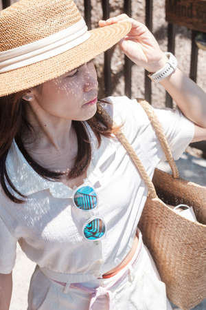 Happy traveler woman in white dress and hat e, young woman standing and looking ocean at tropical beach. Freedom, relaxing, vacation holiday and summer travel conceptの写真素材