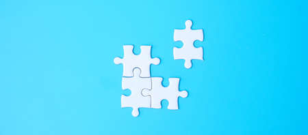 Group of white puzzle jigsaw pieces on blue background. Concept of solutions, mission, success, goals, cooperation, partnership, strategy and puzzle dayの写真素材