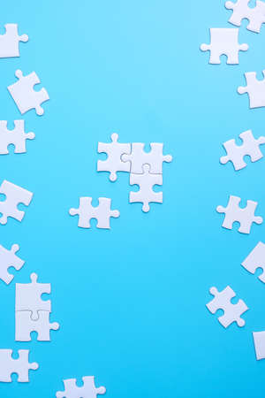 Group of white puzzle jigsaw pieces on blue background. Concept of solutions, mission, success, goals, cooperation, partnership, strategy and puzzle dayの写真素材