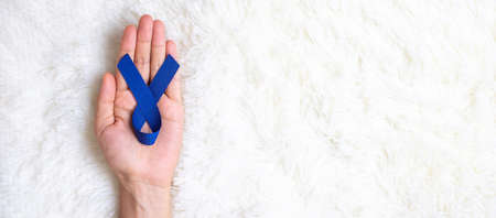 March Colorectal Cancer Awareness month, Man holding dark Blue Ribbon for supporting people living and illness. Healthcare, hope and World cancer day conceptの写真素材