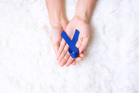 March Colorectal Cancer Awareness month, Man holding dark Blue Ribbon for supporting people living and illness. Healthcare, hope and World cancer day conceptの写真素材