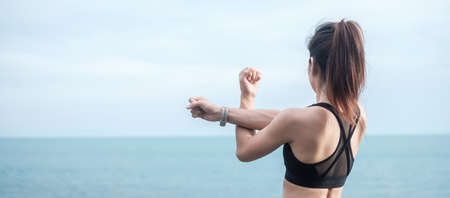 Young fitness female in sportswear stretching body against ocean view, healthy woman exercise in...