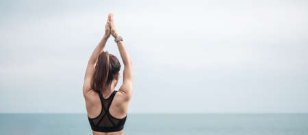 Young woman doing Yoga and stretching muscle in morning, healthy girl meditation against ocean view....