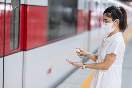 woman clean hand by alcohol gel sanitizer in train or public transportation, protection Coronavirus disease infection. Personal hygiene, safety and travel transport under COVID-19 conceptsの写真素材