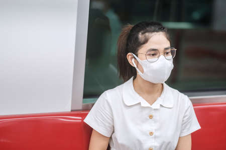 woman wearing Medical face mask and listening music by earphones in train.の写真素材