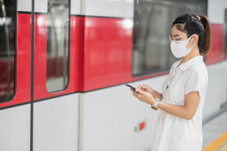 woman using smartphone during wearing protective face mask in train.の写真素材