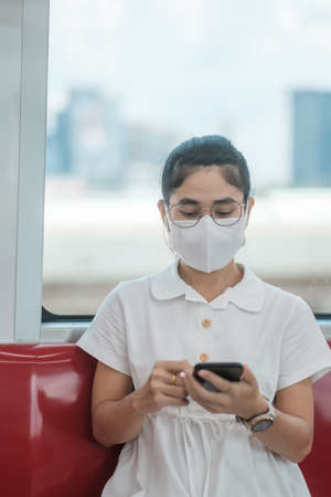 woman using smartphone during wearing protective face mask in train.の写真素材
