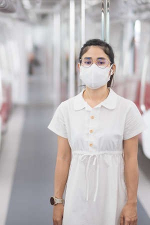 woman wearing Medical face mask and listening music by earphones in train.の写真素材