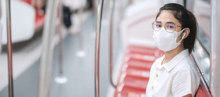 woman wearing Medical face mask and listening music by earphones in train.の写真素材