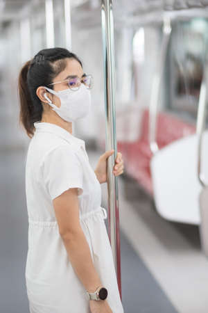 woman wearing Medical face mask and listening music by earphones in train.の写真素材