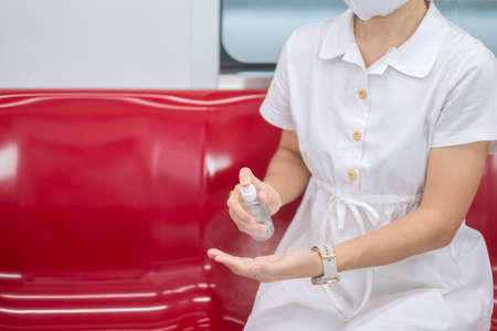 woman clean hand by alcohol spray sanitizer in train or public transportationの写真素材