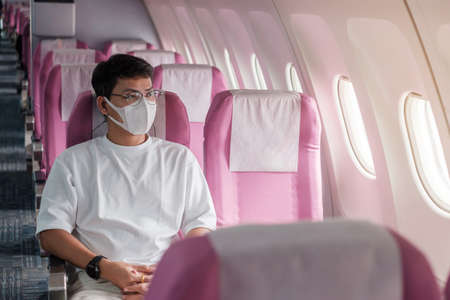 man wearing protective face mask in airplane or public transportation, protection  disease infection, Asian tourist ready to travel. Next Normal and reopening conceptの写真素材