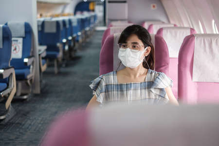 Young woman wearing protective face mask in airplane or public transportation, protection  disease infection, Asian tourist ready to travel. Next Normal and reopening conceptの写真素材