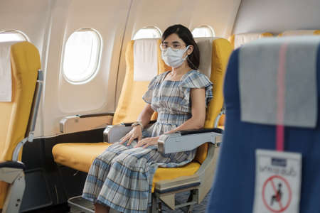 woman wearing protective face mask sitting in airplane or public transportationの写真素材