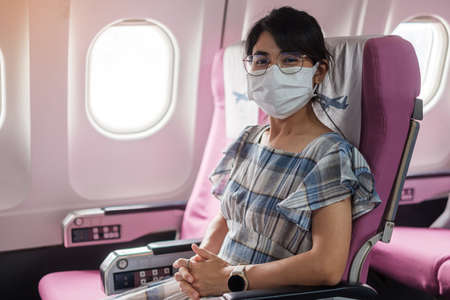 woman wearing protective face mask sitting in airplane or public transportationの写真素材