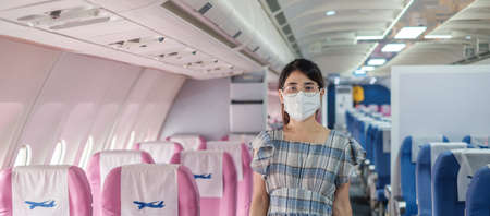 woman wearing protective face mask sitting in airplane or public transportationの写真素材