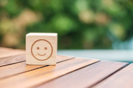 Smile emotion face symbol on wooden blocks. Service rating, ranking, customer review, satisfaction, evaluation and feedback conceptの写真素材