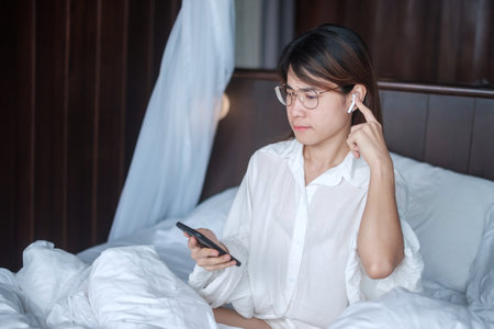 Happy woman using smart phone for video call, female meeting  online by mobile phone on bed. technology, network, work frome home, lifestyle and digital communication conceptの写真素材