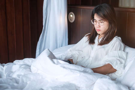 woman having migraine headaches during lying in bed at home. insomnia, sleepless, tired, suffering and stressed conceptsの写真素材