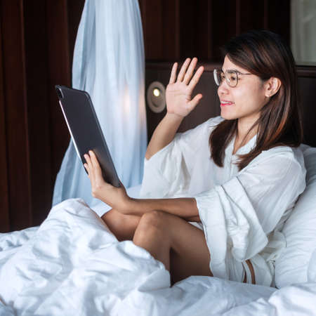 Happy woman using tablet for video call, female meeting  online by computer pad on bed. technology, network, work frome home, lifestyle and digital communication conceptの写真素材
