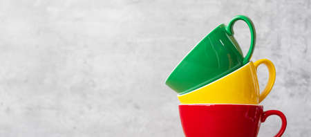 stack of colorful coffee cups on wall background at cafe. Green, yellow and red color ceramic mug on table at home. International coffee day conceptの写真素材