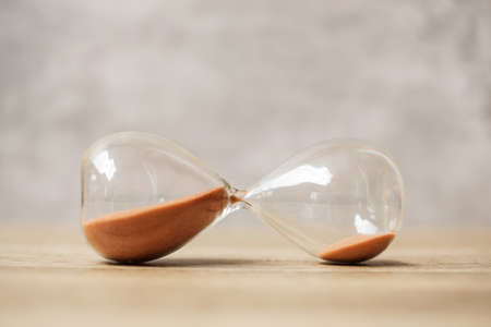 Hourglass on table, Sand flowing through the bulb of Sandglass measuring the passing time....
