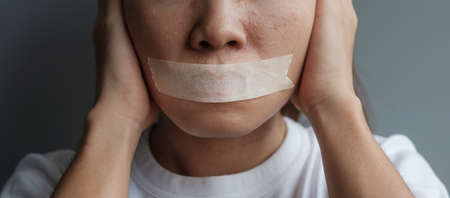 woman with mouth sealed in adhesive tape. Free of speech, freedom of press, Human rights, Protest dictatorship, democracy, liberty, equality and fraternity conceptsの写真素材