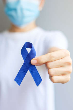 March Colorectal Cancer Awareness month, Woman holding dark Blue Ribbon for supporting people living and illness. Healthcare, hope and World cancer day conceptの写真素材