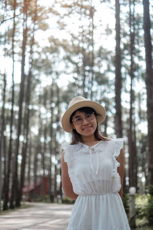 Happy woman in white dress and hat traveling in pine tree forest, tourist visit at Doi Bo Luang, Chiang Mai, Thailand, Landmark and popular for tourist attractions. Vacation and journey conceptの写真素材