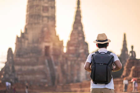 Tourist Man with backpack visiting to ancient stupa in Wat Chaiwatthanaram temple in Ayutthaya Historical Park, summer, solo, Asia and Thailand travel conceptの写真素材