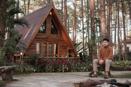 Happy man in sweater traveling in pine tree forest, tourist visit at Doi Bo Luang, Chiang Mai, Thailand, Landmark and popular for tourist attractions. Vacation and journey conceptの写真素材