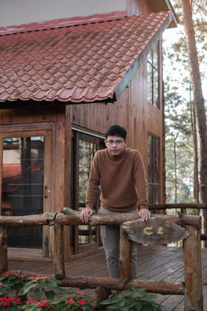 Happy man in sweater traveling in pine tree forest, tourist visit at Doi Bo Luang, Chiang Mai, Thailand, Landmark and popular for tourist attractions. Vacation and journey conceptの写真素材