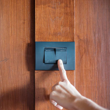 finger turn on or off on light switch on wall at home. Energy Saving, power, electrical and lifestyle conceptsの写真素材