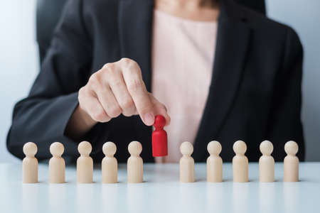 Businesswoman hand pulling leader man wooden from crowd of employees. Toxic People, Human resource management, Recruitment, Teamwork and leadership Conceptsの写真素材