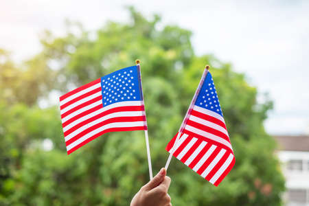 hand holding United States of America flag on green background. USA holiday of Veterans, Memorial, Independence ( Fourth of July) and Labor Day conceptの写真素材