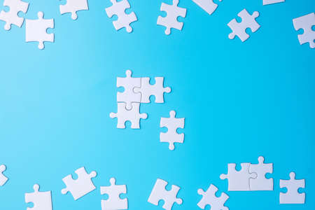 Group of white puzzle jigsaw pieces on blue background. Concept of solutions, mission, success, goals, cooperation, partnership, strategy and puzzle dayの写真素材