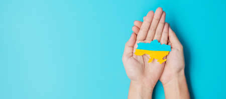 Support for Ukraine in the war with Russia, Hands holding the shape of Ukraine border with color flag. Pray, No war, stop war and stand with Ukraineの写真素材