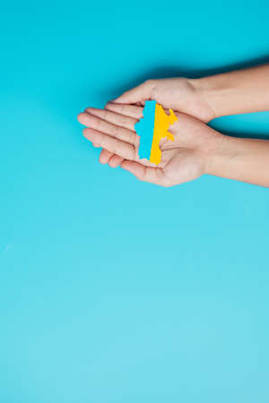 Support for Ukraine in the war with Russia, Hands holding the shape of Ukraine border with color...