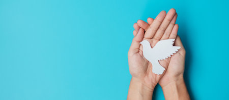 International Day of Peace. Hands holding white paper Dove bird on blue background. Freedom, Hope and World Peace day 21 September concepts..の写真素材