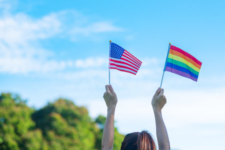 hands showing LGBTQ Rainbow and America flag on nature background. Support Lesbian, Gay, Bisexual, Transgender and Queer community and Pride month conceptの写真素材