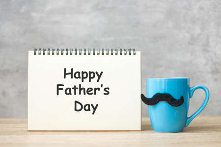 Happy Father day with paper notepad, Blue coffee cup or tea mug and Black mustache decor on table. International men day and celebration conceptの写真素材