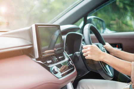 woman driver driving a car on the road, hand controlling steering wheel in electric modern...