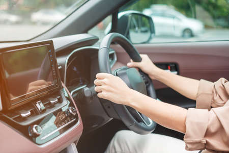 woman driver driving a car on the road, hand controlling steering wheel in electric modern automobile. Journey, trip and safety Transportation conceptsの写真素材