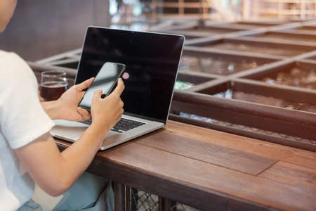 Casual Businesswoman using smartphone and laptop, freelance woman typing keyboard computer notebook...