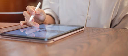 woman using tablet for sms messages, hand holding pencil typing touchscreen mobile phone in cafe or modern office. lifestyle, technology, Social media and network conceptの写真素材
