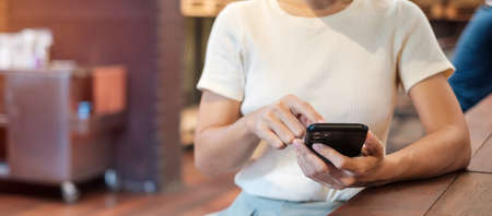 Casual Businesswoman holding and using smartphone for sms messages, young woman typing touchscreen...